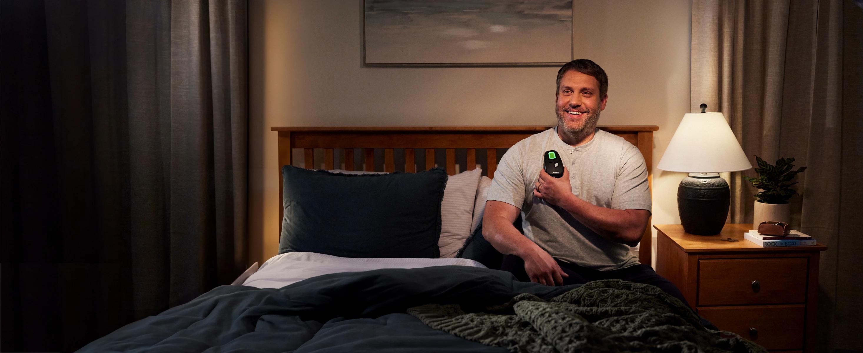 Smiling man in bed touching Inspire device