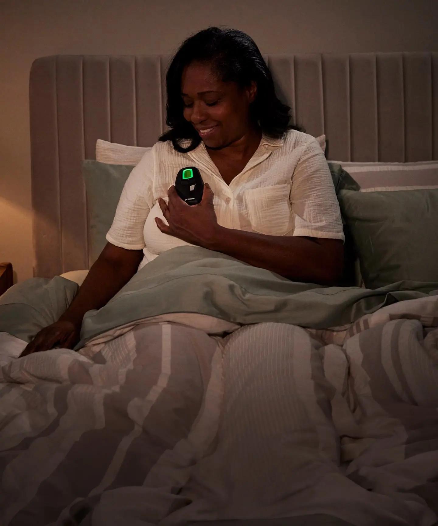 Woman using an Inspire Therapy remote and device before going to sleep.