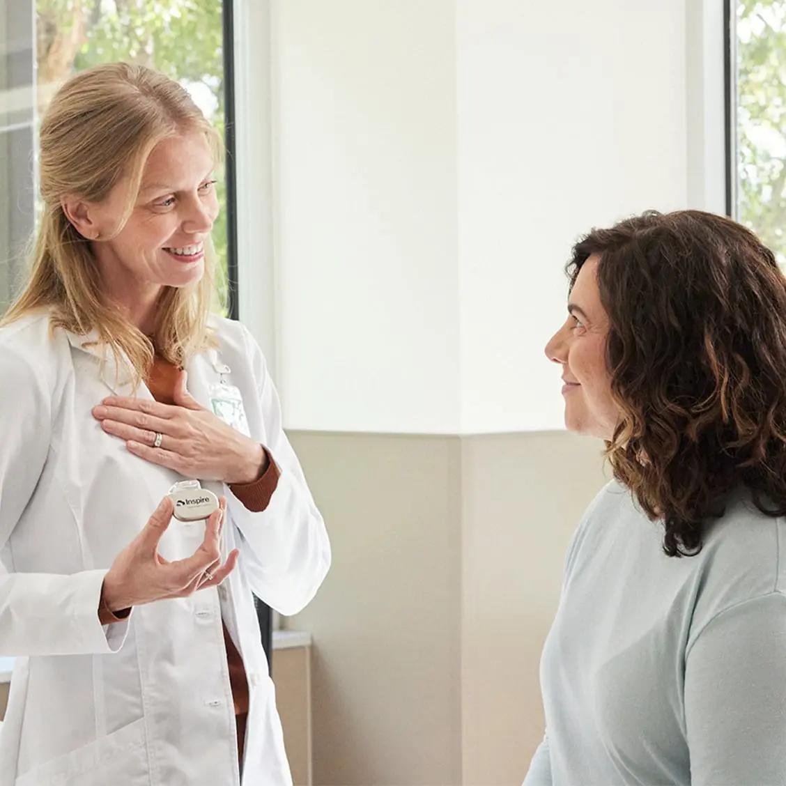 The image shows two women engaged in a conversation about the Inspire Implant.