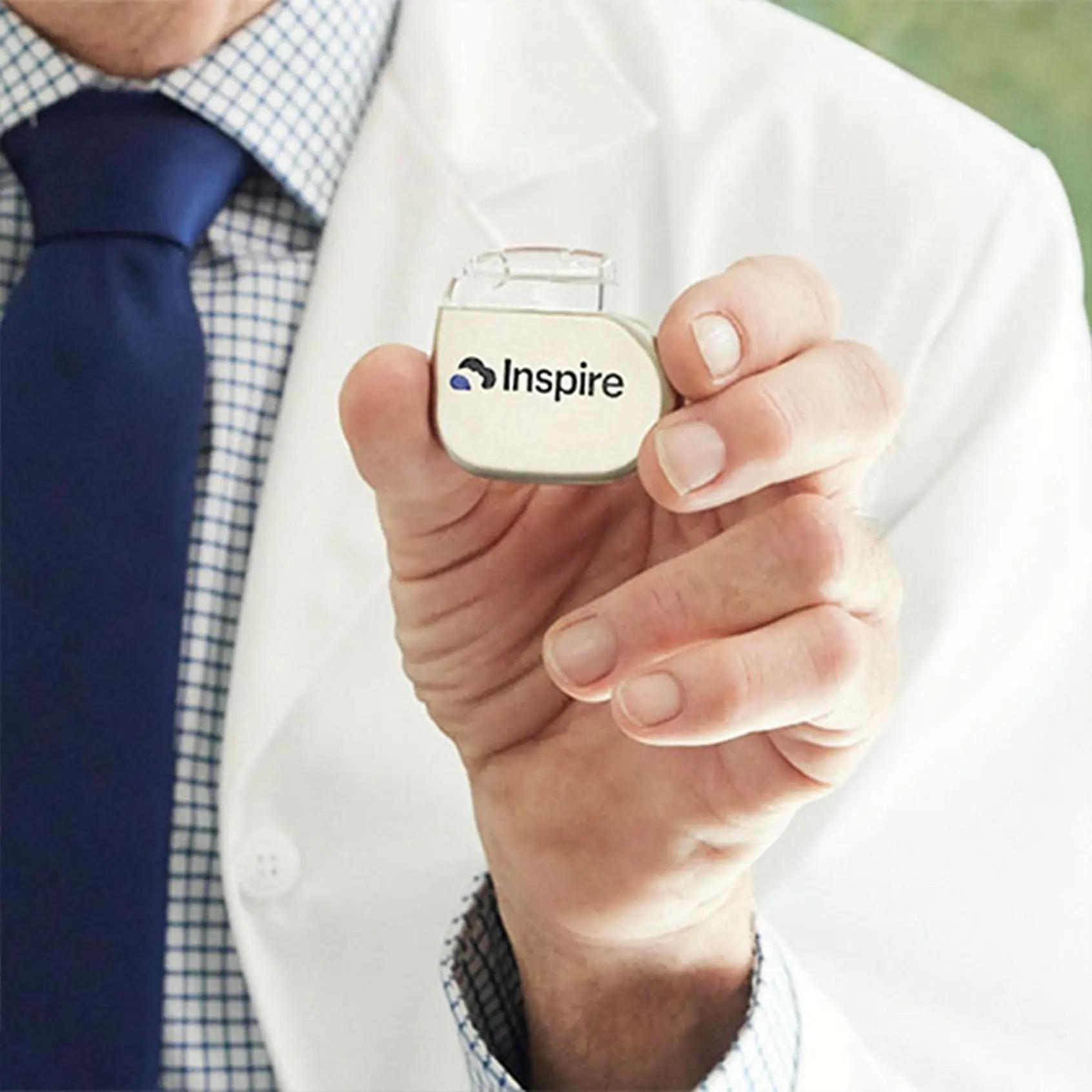 The image shows a doctor holding an Inspire implant.